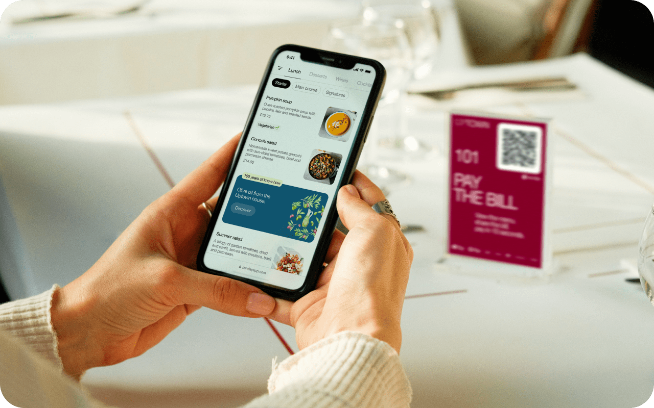 Customer browsing a digital menu on their phone at a restaurant table with a QR code tent card